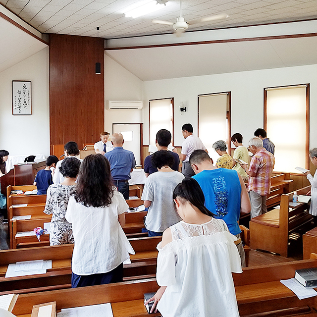 夏場の礼拝風景。これは皆で讃美歌を歌っているところ。「教会にはどんな服装で行ったらいいですか？」とよく聞かれますが、御覧のように普段着でまったく問題ありません。（一番奥でネクタイを締めている人は牧師です）
座席は十分な空きが用意されています。初めての方には、全体が見渡せる後ろの席がおすすめです。