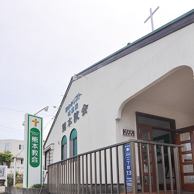 熊本教会の外観です。屋根上の十字架とグリーンの看板が目印です。