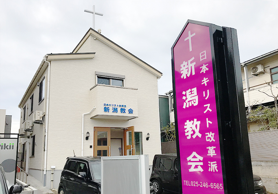 日本キリスト改革派 新潟教会の外観写真。道路に面した看板と屋根上の十字架が目印です。
