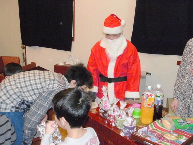 日曜学校 子どもクリスマス会でお菓子を配るサンタクロース。