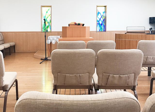 モリーさんの この一枚「西谷教会の座席は全席自由。お好きな席にお座りください。写真は正面中央の席に座ったところ。前列の椅子に専用のポケットが用意されていますので聖書や讃美歌を収納することが可能です。」