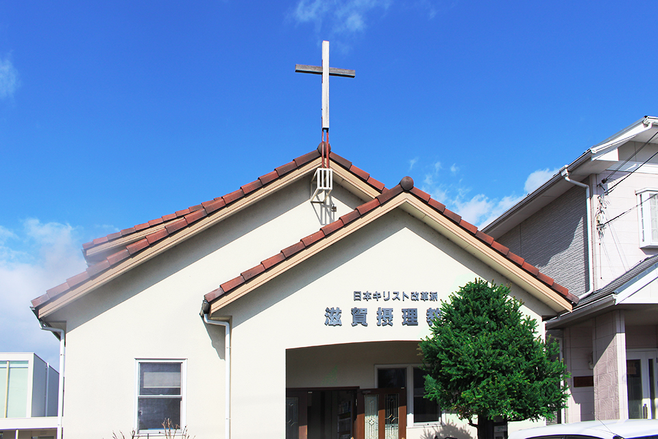 日本キリスト改革派 滋賀摂理教会の外観写真。赤い屋根と十字架が目印です。