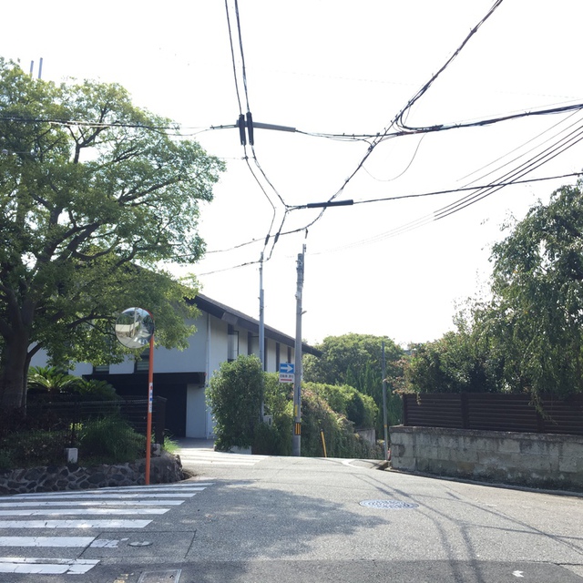 駅正面の道を進むとこの五差路に行き当たります。奥のお宅の右側、下り坂を進んでください。